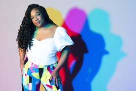 Person in white shirt with colorful prism pants with colorful reflections in background